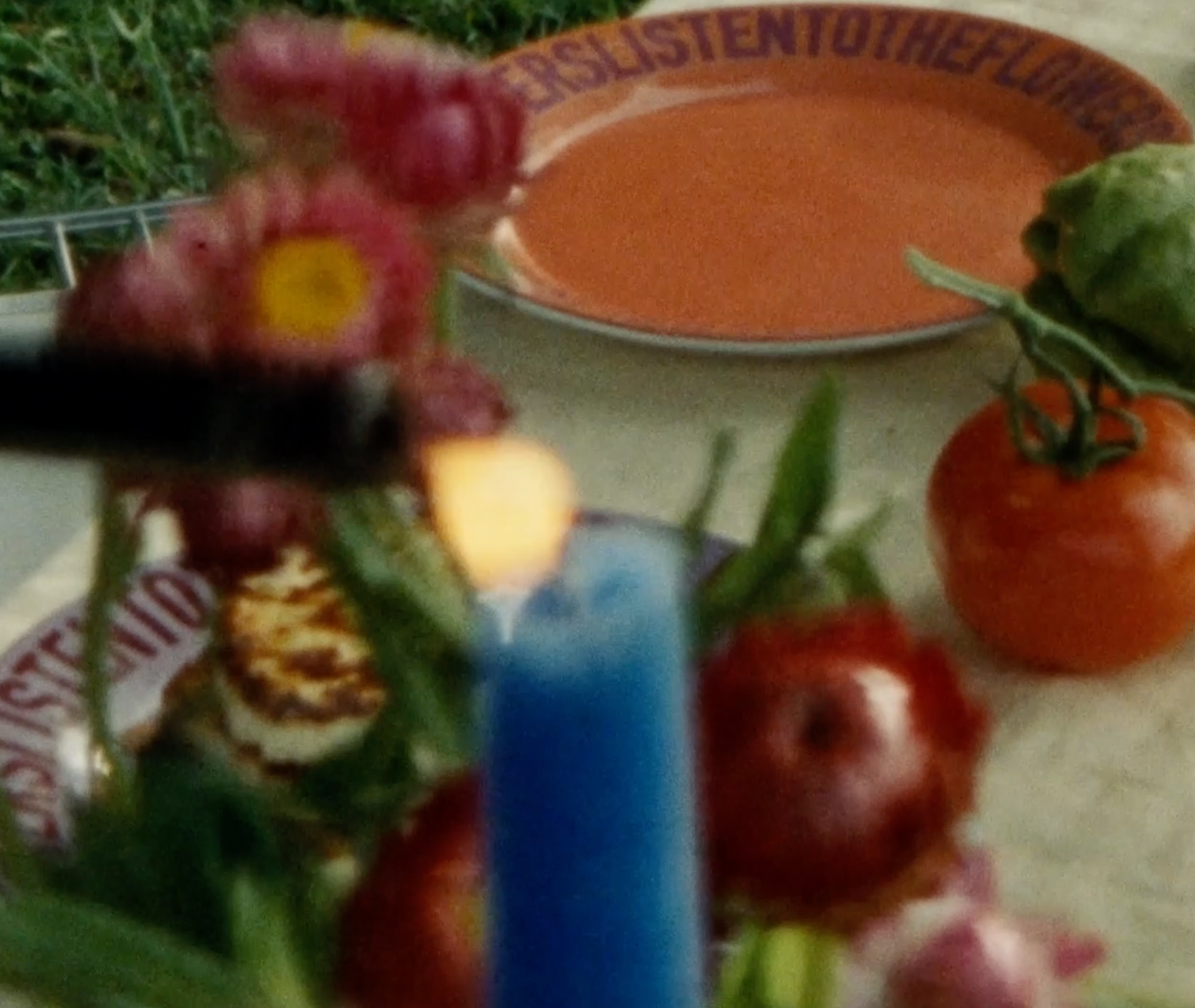 Orange ceramic plate on table with flowers and blue candle