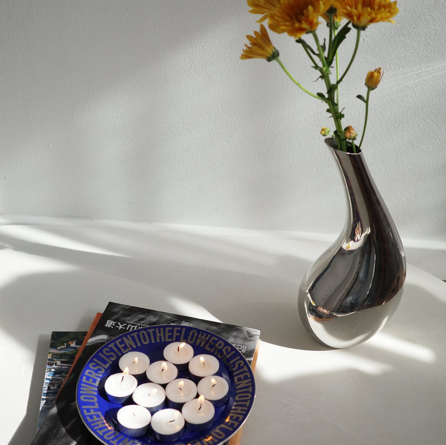 DARK BLUE CERAMIC PLATES WITH CHROME VASE AND YELLOW FLOWERS