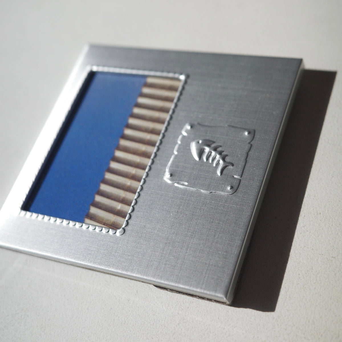 smal square metal picture frame with an embossed fish
